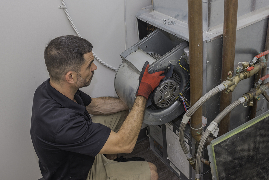 A hard working HVAC technician inspects the filter in an air cooling system.