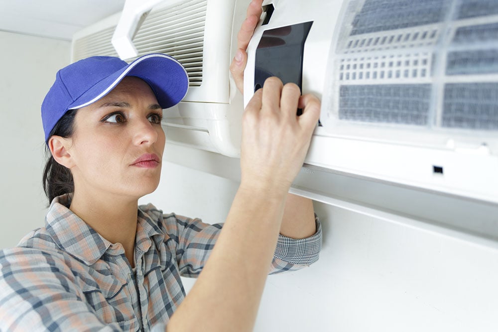 woman HVAC technician fixing an air conditioning system