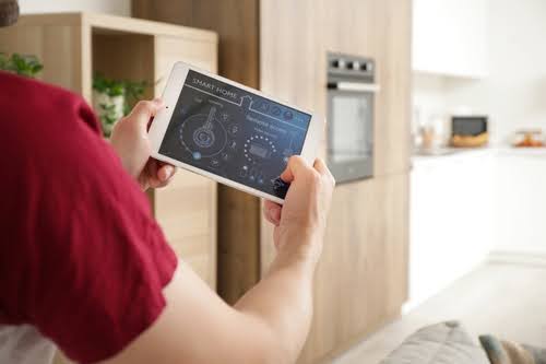 Person holding Ipad in smart home.