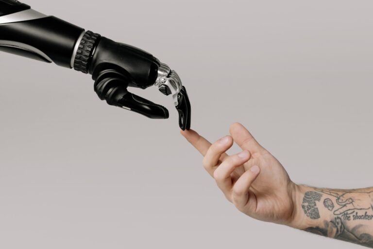 Human hand touching a robotic hand.