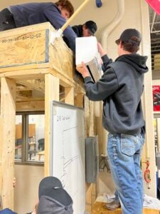 Four male students working on an air conditioner