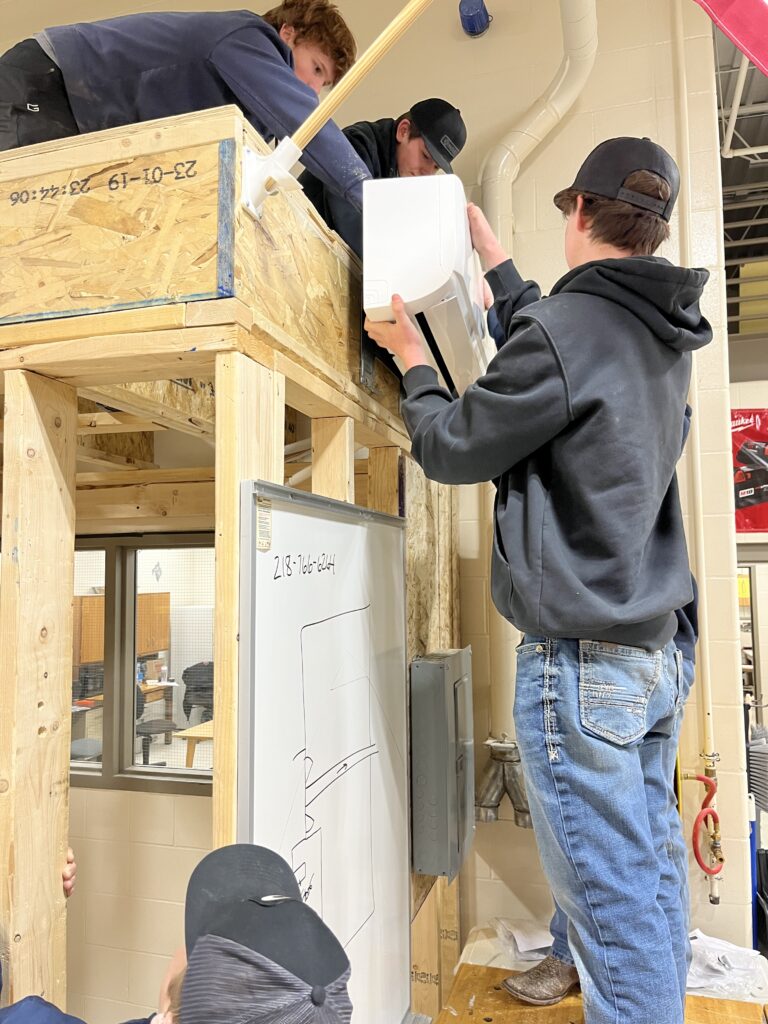Four male students working on an air conditioner