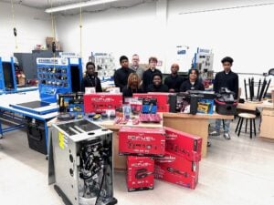 Students and a teacher standing next to boxes of tools