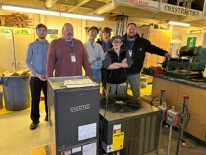 Students and two teachers standing behind an air conditioner