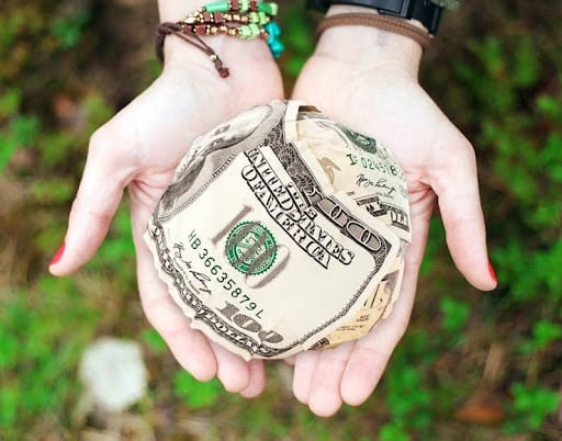 Hands holding $100 bills.