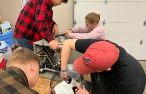 Three male and one female student working on an air conditioner