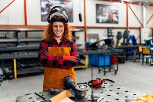 A young woman poses in front of her workshop.