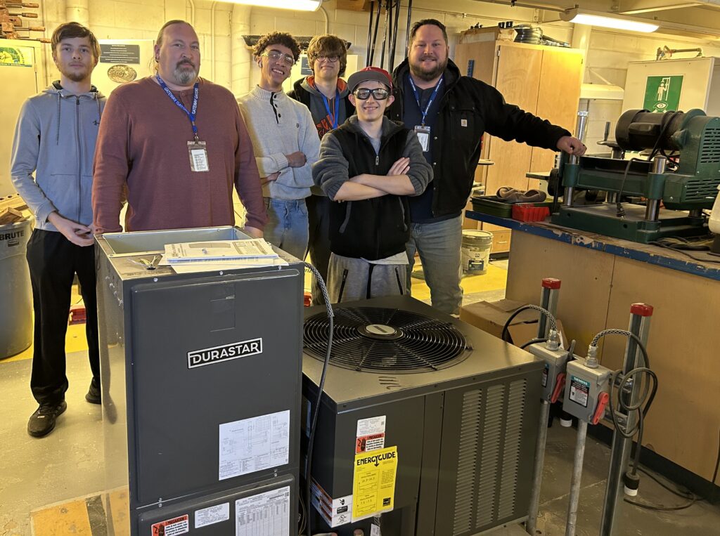 Teacher and students stand behind an air conditioner
