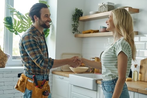 A tradesman shakes hand with a homeowner.