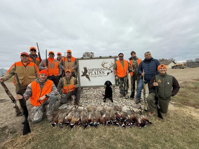 Men standing behind a row of pheasants.