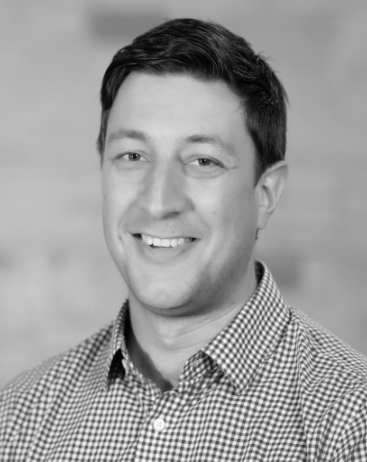 Man smiling in a black and white photo.