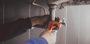 A plumber uses a wrench to fix a pipe.