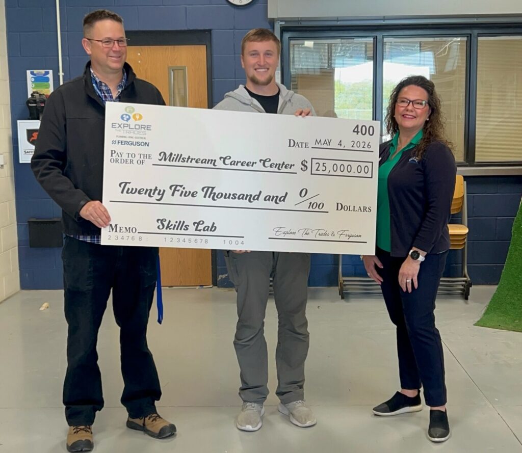 Three people standing behind a large check.