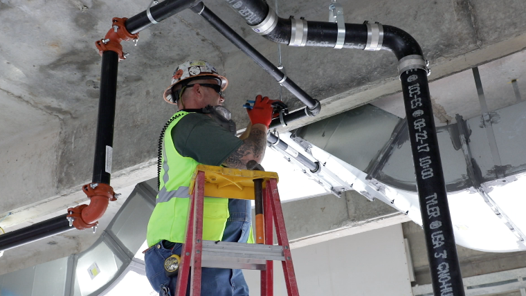 Apprentice or technician inspecting a commercial fire sprinkler valve system.