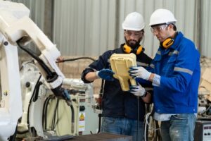 Two workers program a robot arm