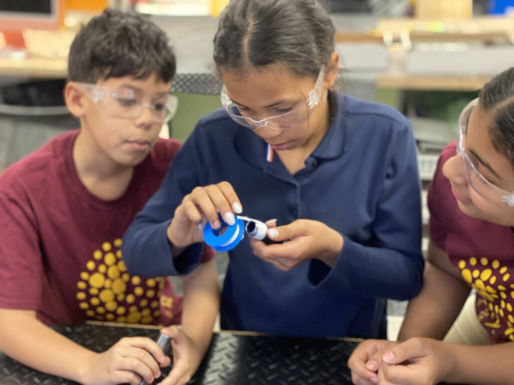 Three students working on plumbing equipment.